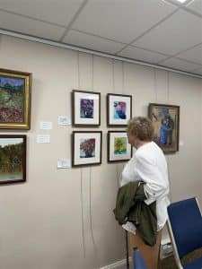 A resident views framed floral paintings on the gallery wall.